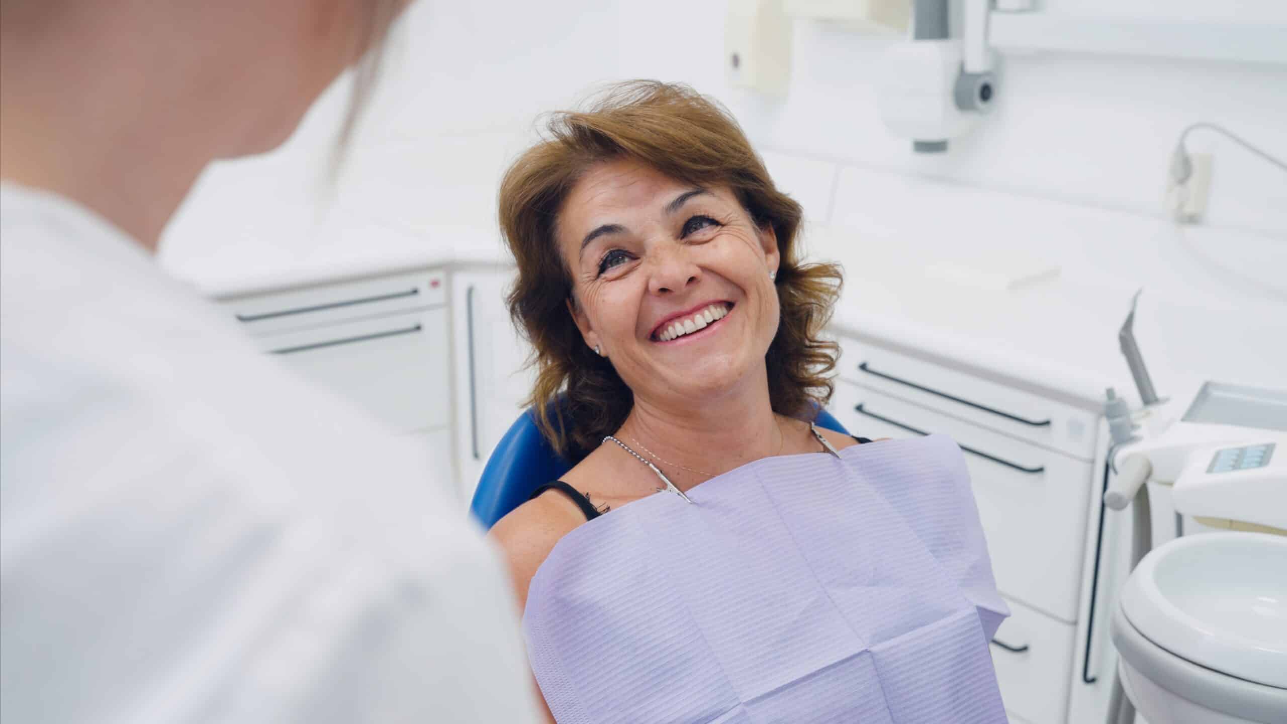 Mature,Woman,Patient,Smiling,Happily,,Looking,Up,At,The,Dental