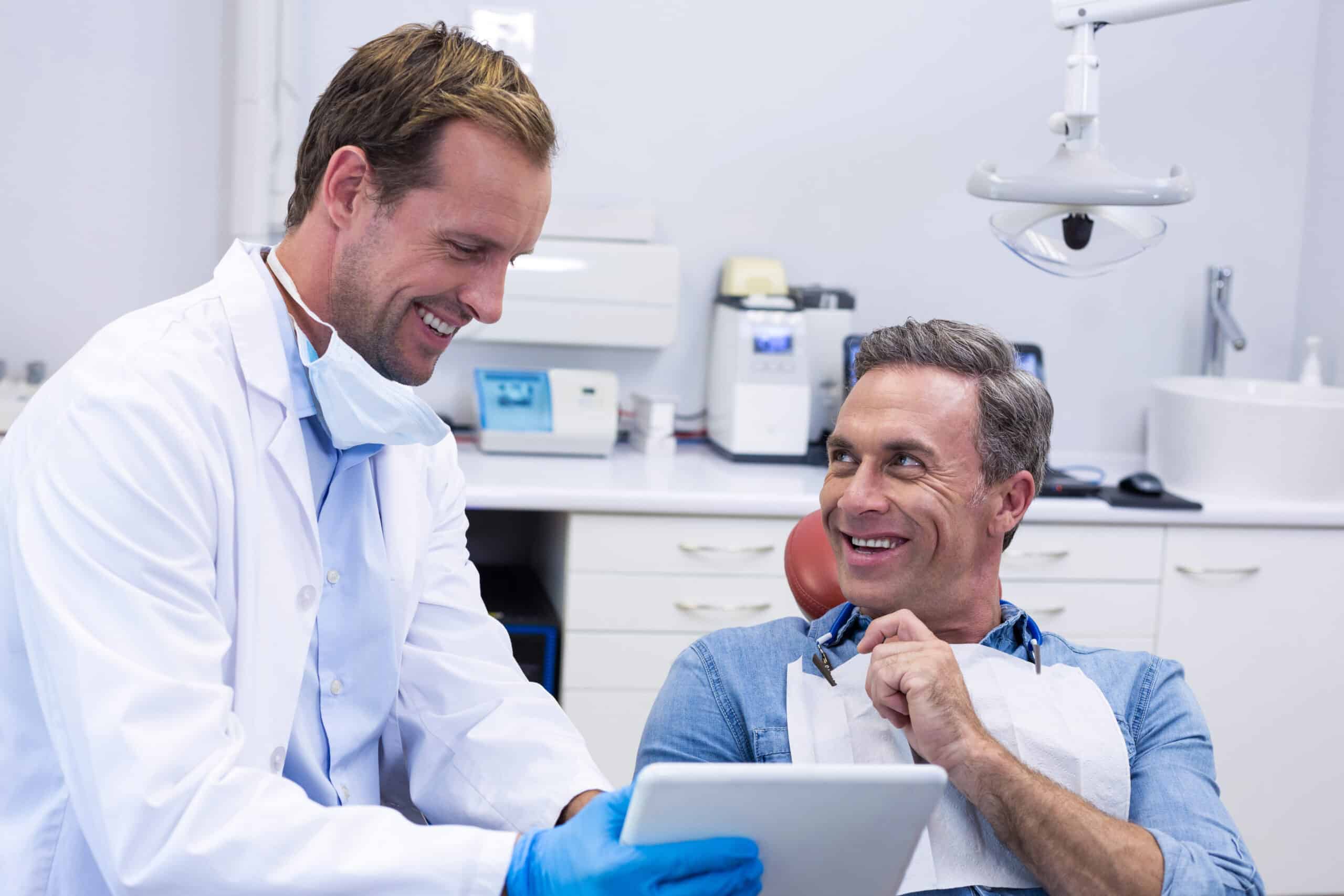 Dentist,Discussing,Over,Digital,Tablet,With,Male,Patient,In,Dental