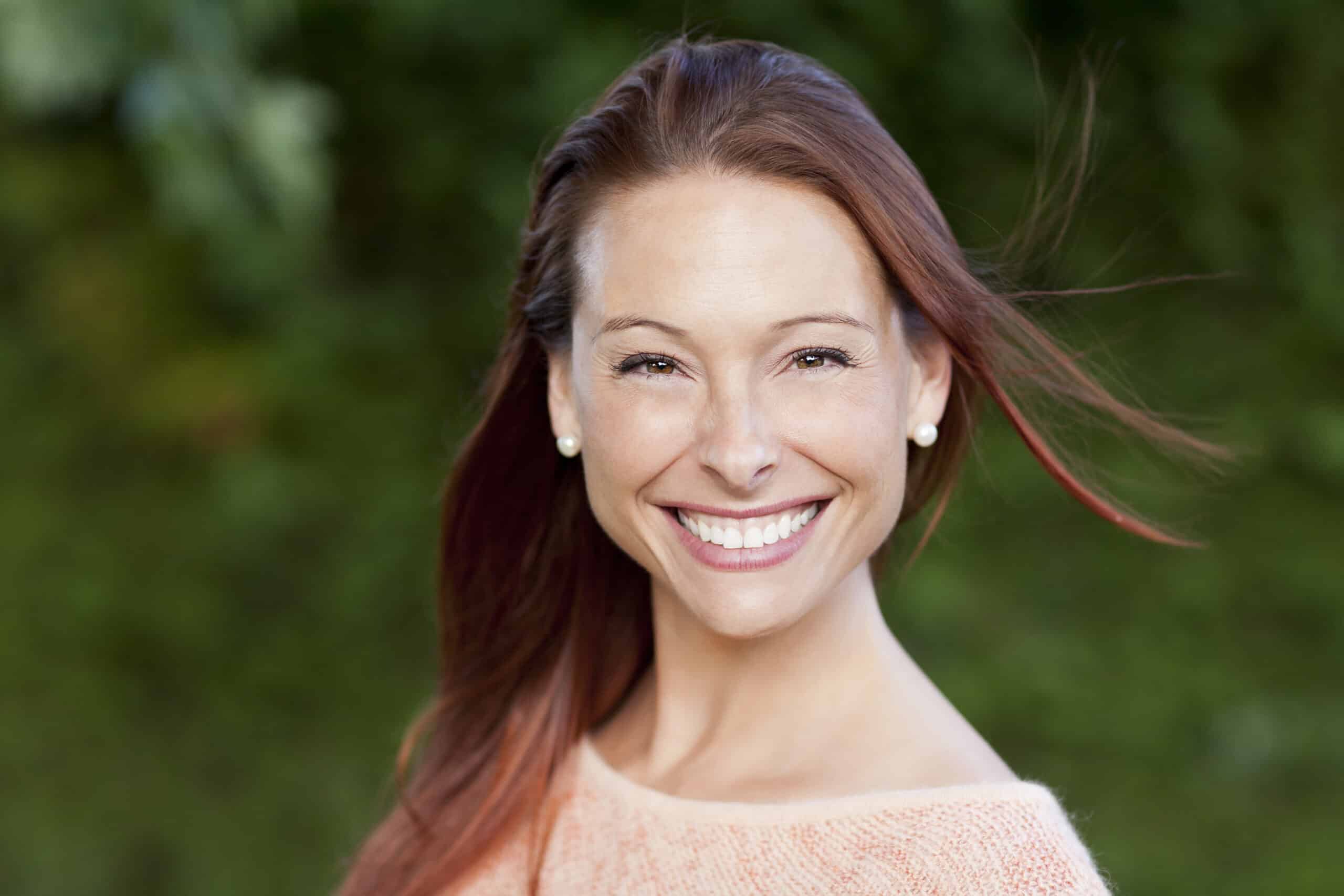 Smiling,Woman,Outside,Looking,At,The,Camera