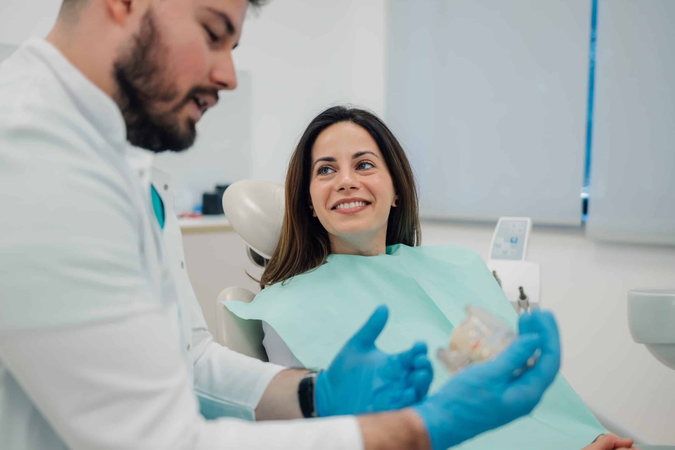 Dentist,Wearing,Blue,Gloves,Showing,Dentures,To,A,Smiling,Patient