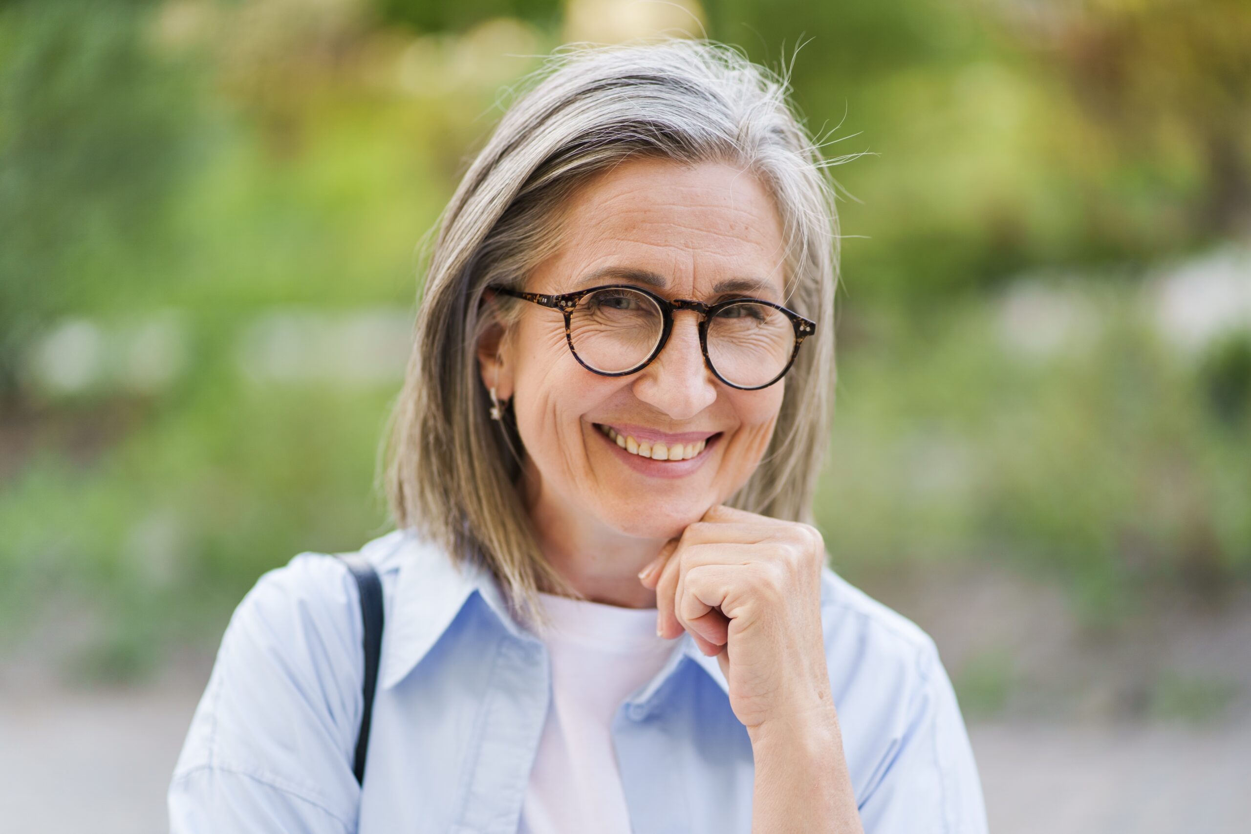 A,Woman,With,Glasses,Is,Smiling,And,Looking,At,The